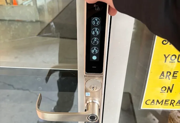 Digital keypad and lever lock on a glass entrance door.