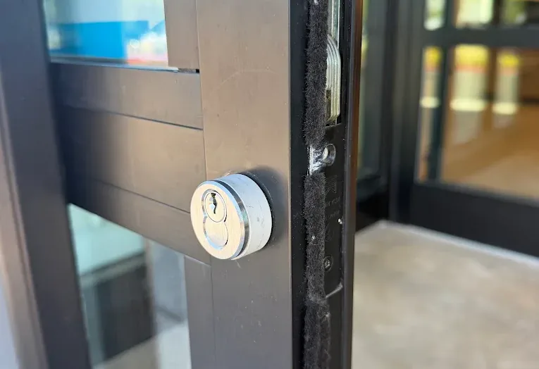 Electronic entry lock mounted on a dark-framed commercial door.