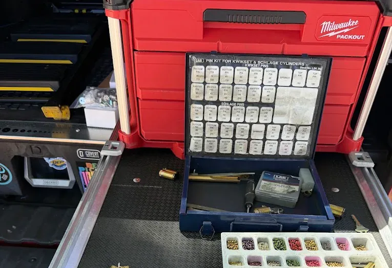 Locksmith pin kit and rekeying supplies arranged in a mobile work vehicle.