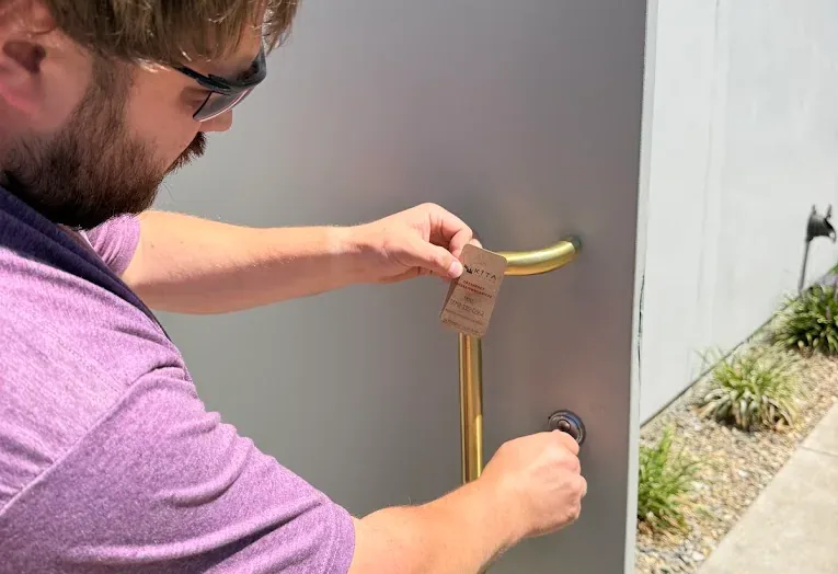 Technician fitting door hardware at an exterior entry.