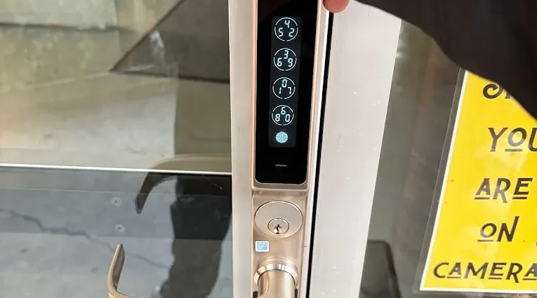 Digital keypad and lever lock on a glass entrance door.