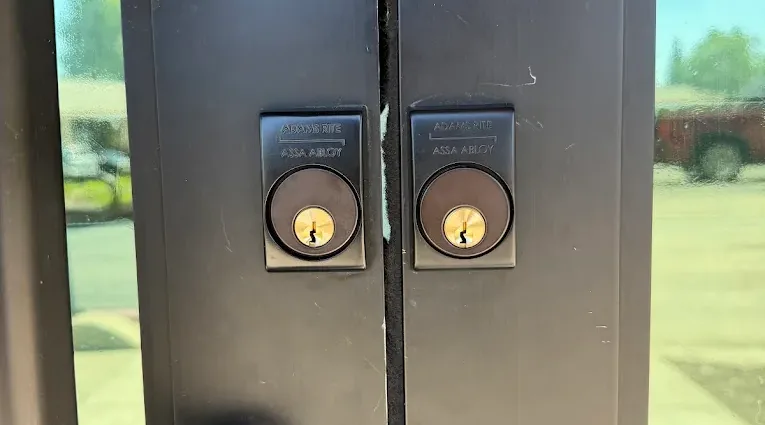 Two lock cylinders on a metal commercial double door.