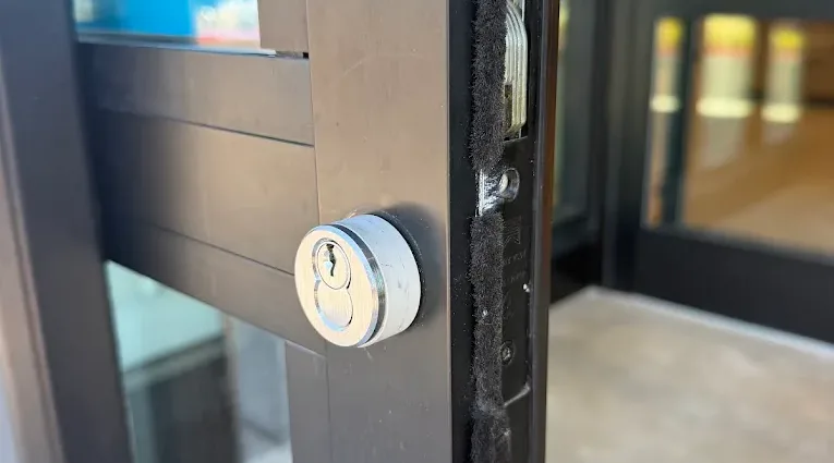 Electronic entry lock mounted on a dark-framed commercial door.