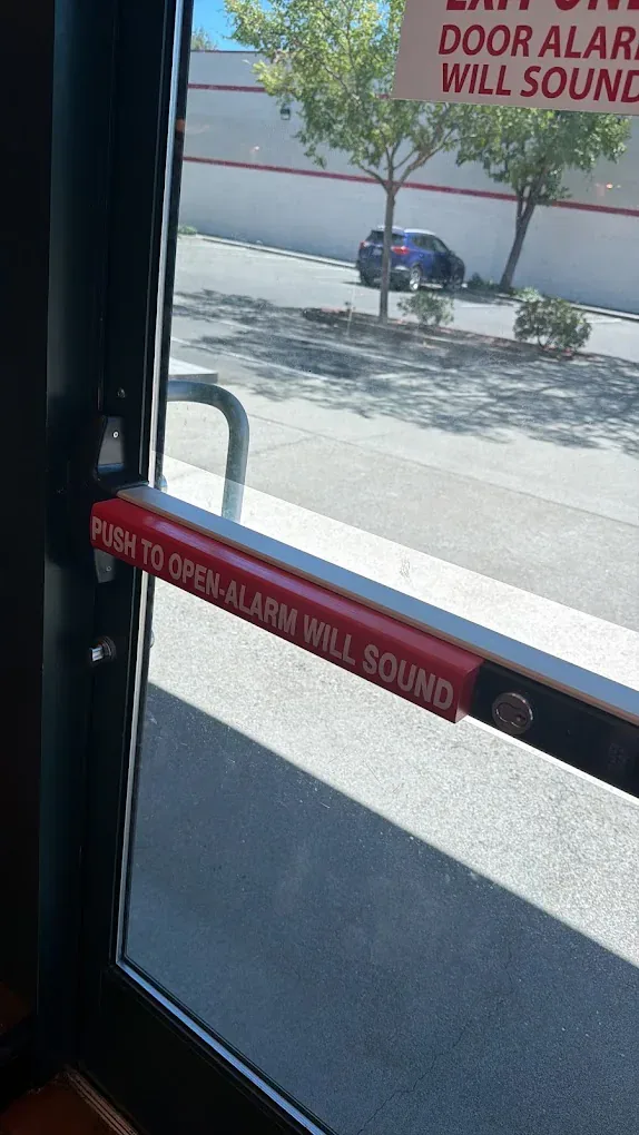 Commercial glass exit door with an alarm warning decal.