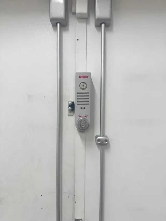 Vertical locking hardware on a metal commercial door.