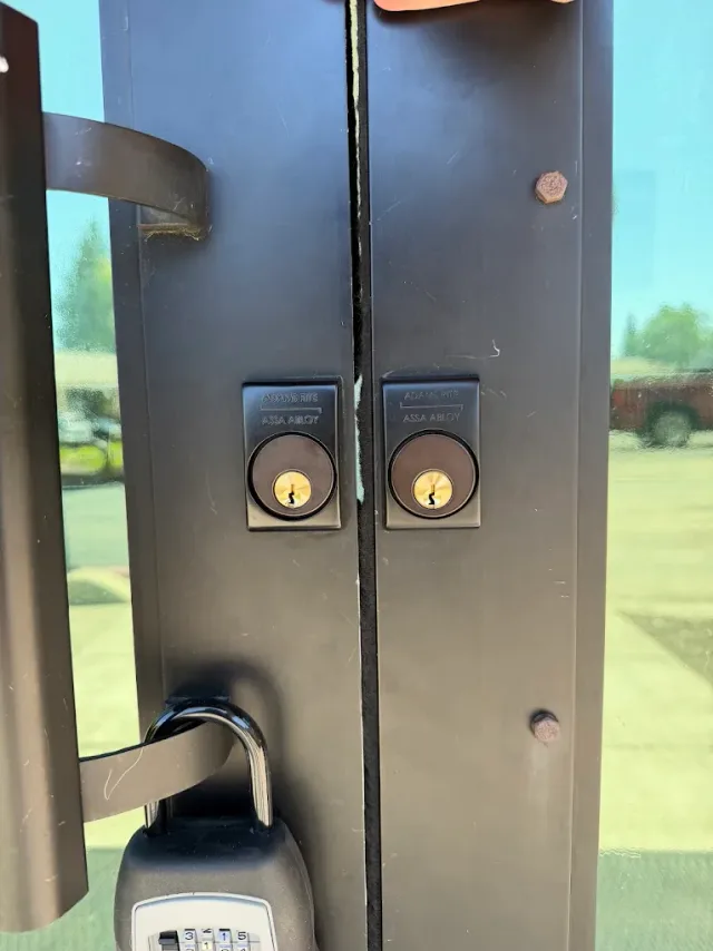Two lock cylinders on a metal commercial double door.