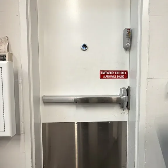 Steel exit door with a horizontal panic bar and safety label